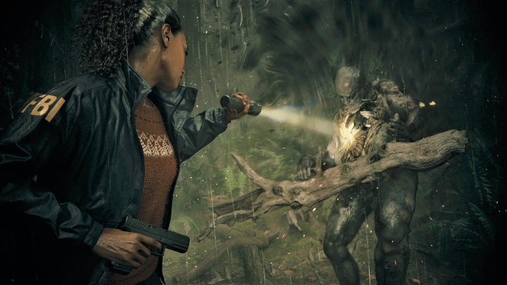 FBI agent Saga Anderson holding a flashlight and gun encounters a mysterious creature in a dark, eerie forest, from Alan Wake 2.