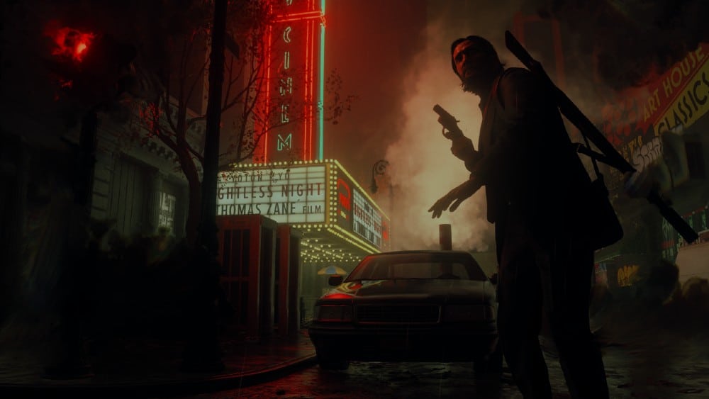 A silhouetted figure with a gun stands in a dimly lit, foggy street near a cinema with a neon sign, from Alan Wake 2.