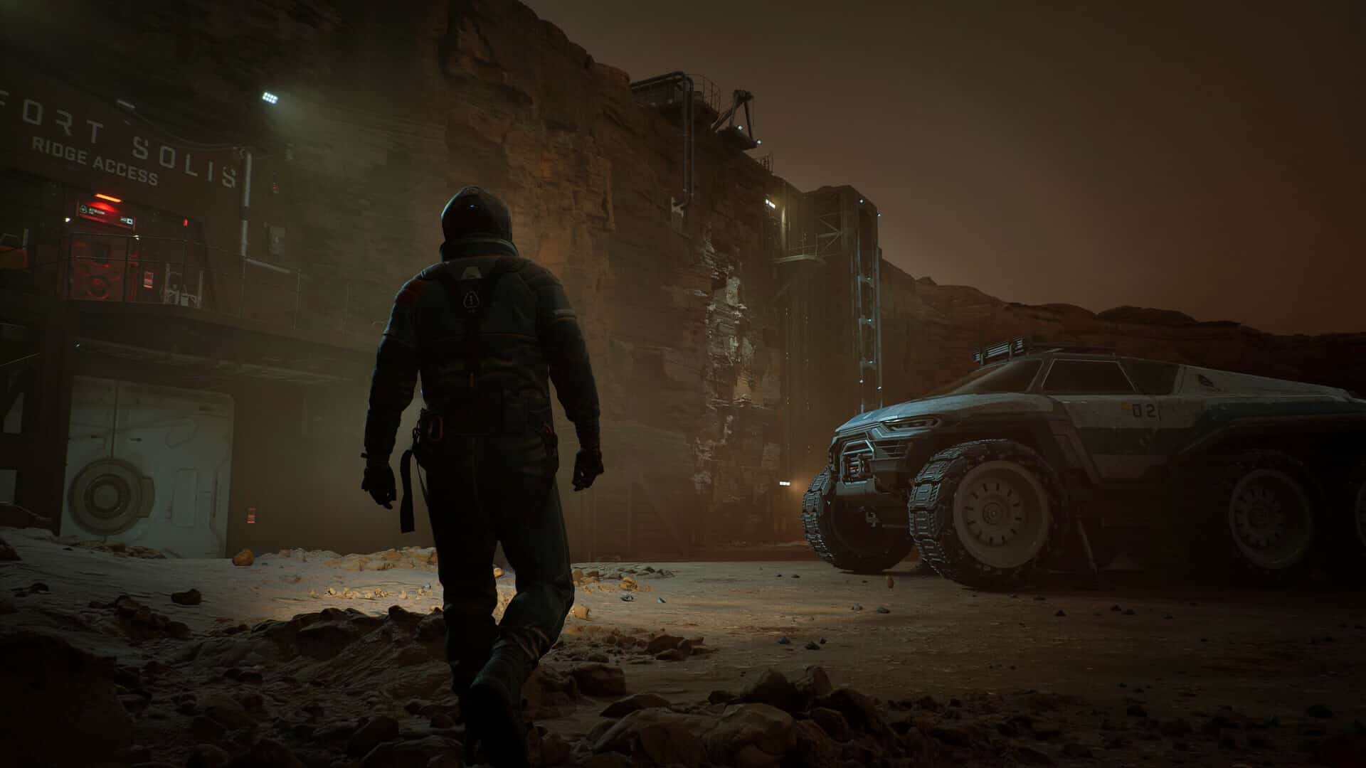 A person in a spacesuit walks toward the illuminated structure of Fort Solis, and an off-road vehicle is parked nearby at night.