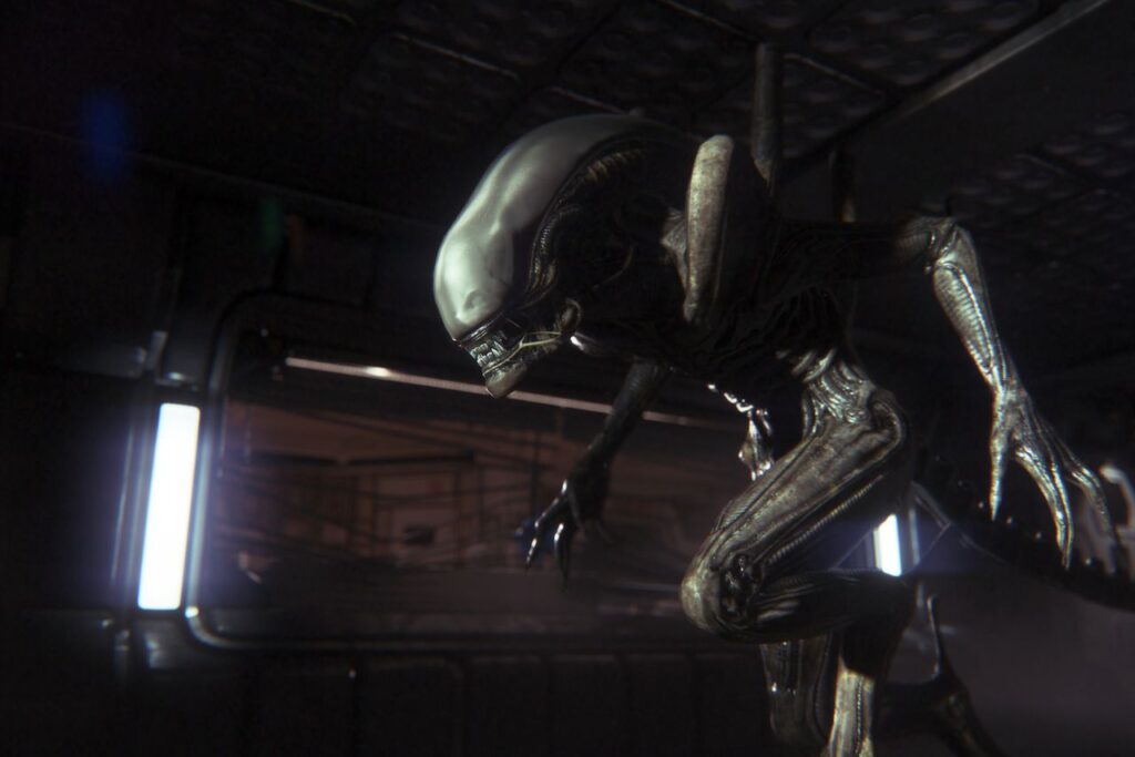 In a dimly lit, metallic corridor in Alien Isolation, a futuristic alien creature crouches, reminiscent of something out of the scariest games to play.