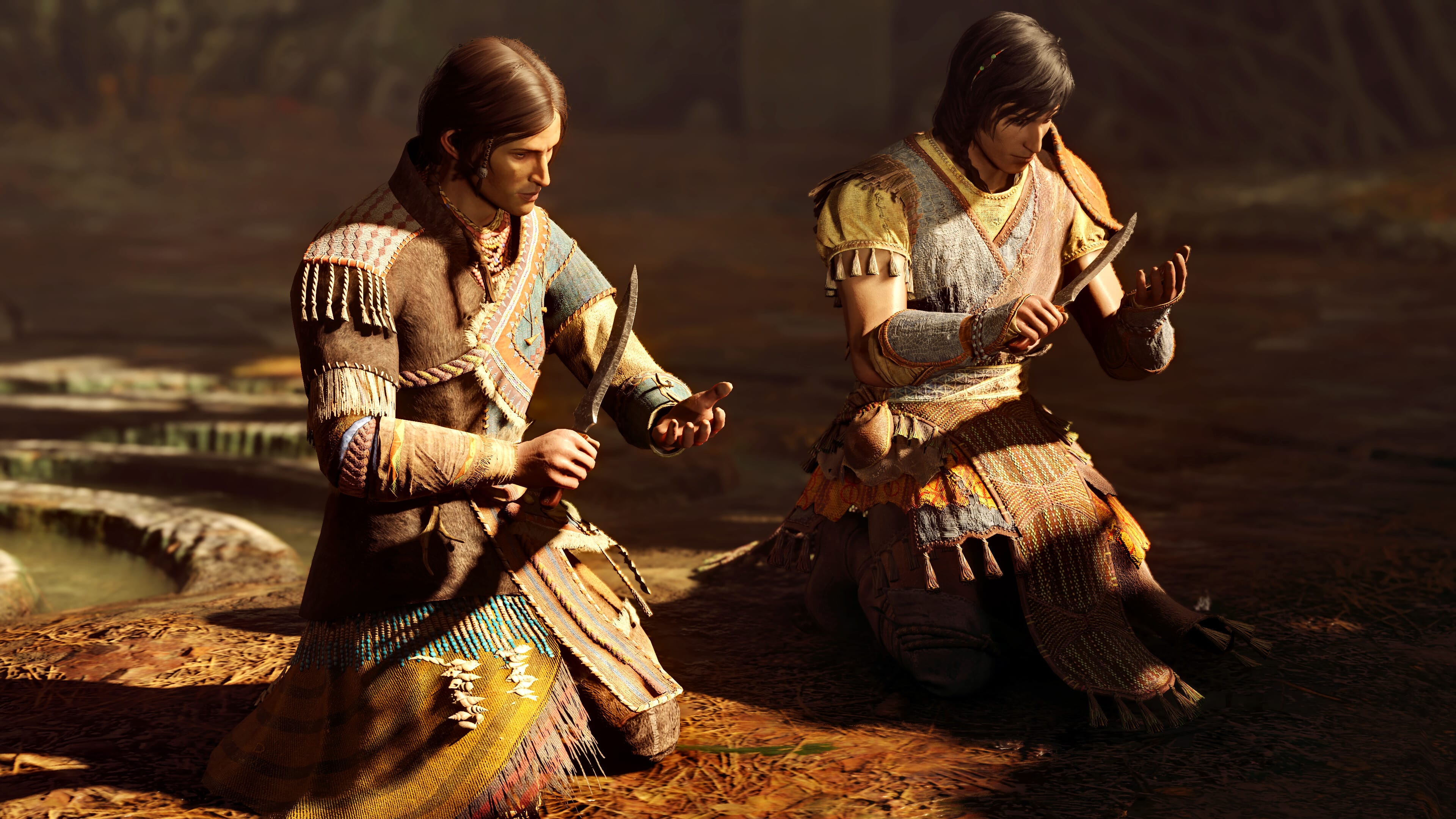 Two people kneeling and examining objects in their hands, adorned in earthy-toned traditional attire, seem immersed in the world of GreedFall II: The Dying World.