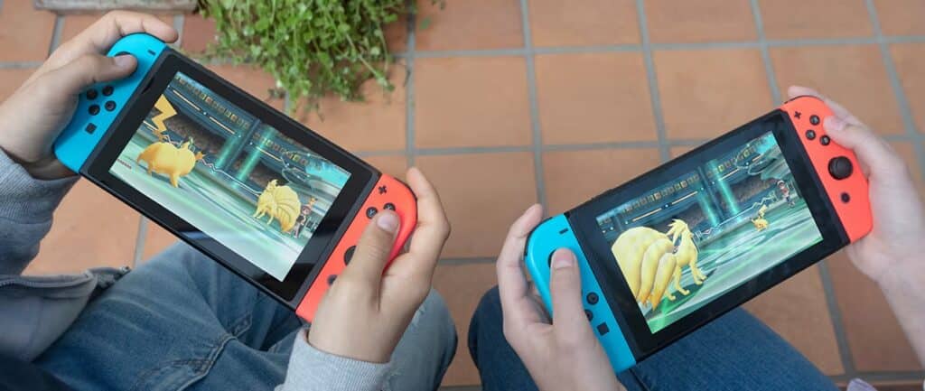 Two people are immersed in Pokémon battles on their Nintendo Switch consoles, featuring striking blue and red controllers. With whispers of the Nintendo Switch 2 and cloud gaming on the horizon, their adventures may soon reach new heights.