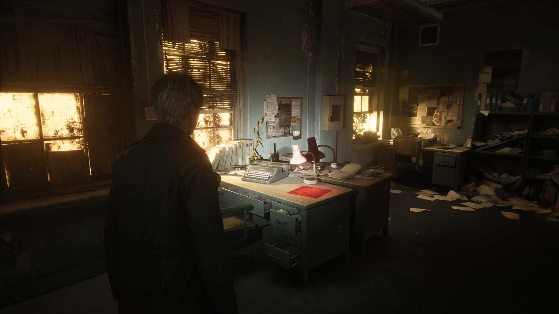 James Sunderland stands in a dimly lit, cluttered office with papers strewn about. The desk lamp casts eerie shadows, while sunlight filters through the blinds, evoking an atmosphere reminiscent of a Silent Hill 2 remake.