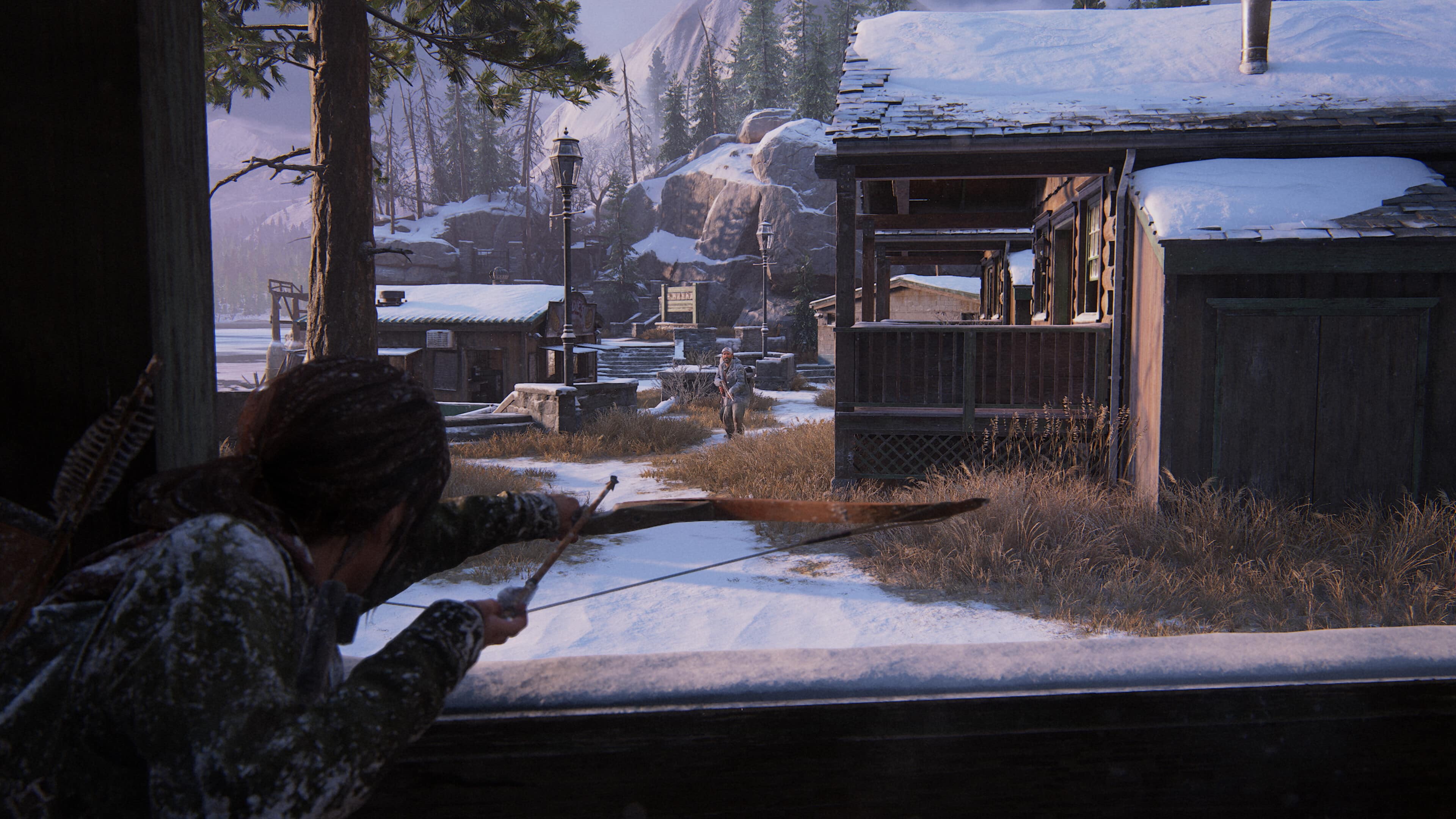 In a scene reminiscent of The Last of Us Part I, Ellie takes aim with a bow, their focus unyielding against the backdrop of a snowy village. Wooden buildings and trees stand silent, enveloped in an air of suspense and survival.