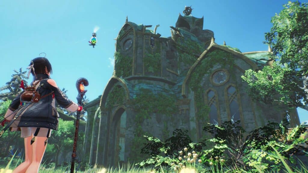 A character from Atelier Yumia: The Alchemist of Memories, with staff in hand, gazes at an ancient, ivy-covered building under the expansive blue skies.