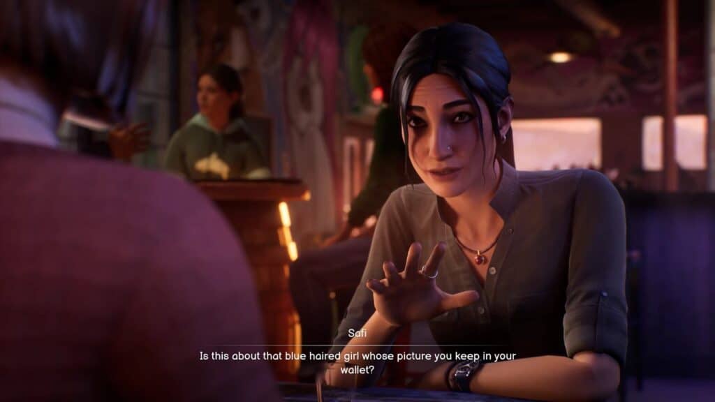 A dark-haired woman in a cafe talks to another person, gesturing with her hand as they discuss the best video games to play with your boyfriend.