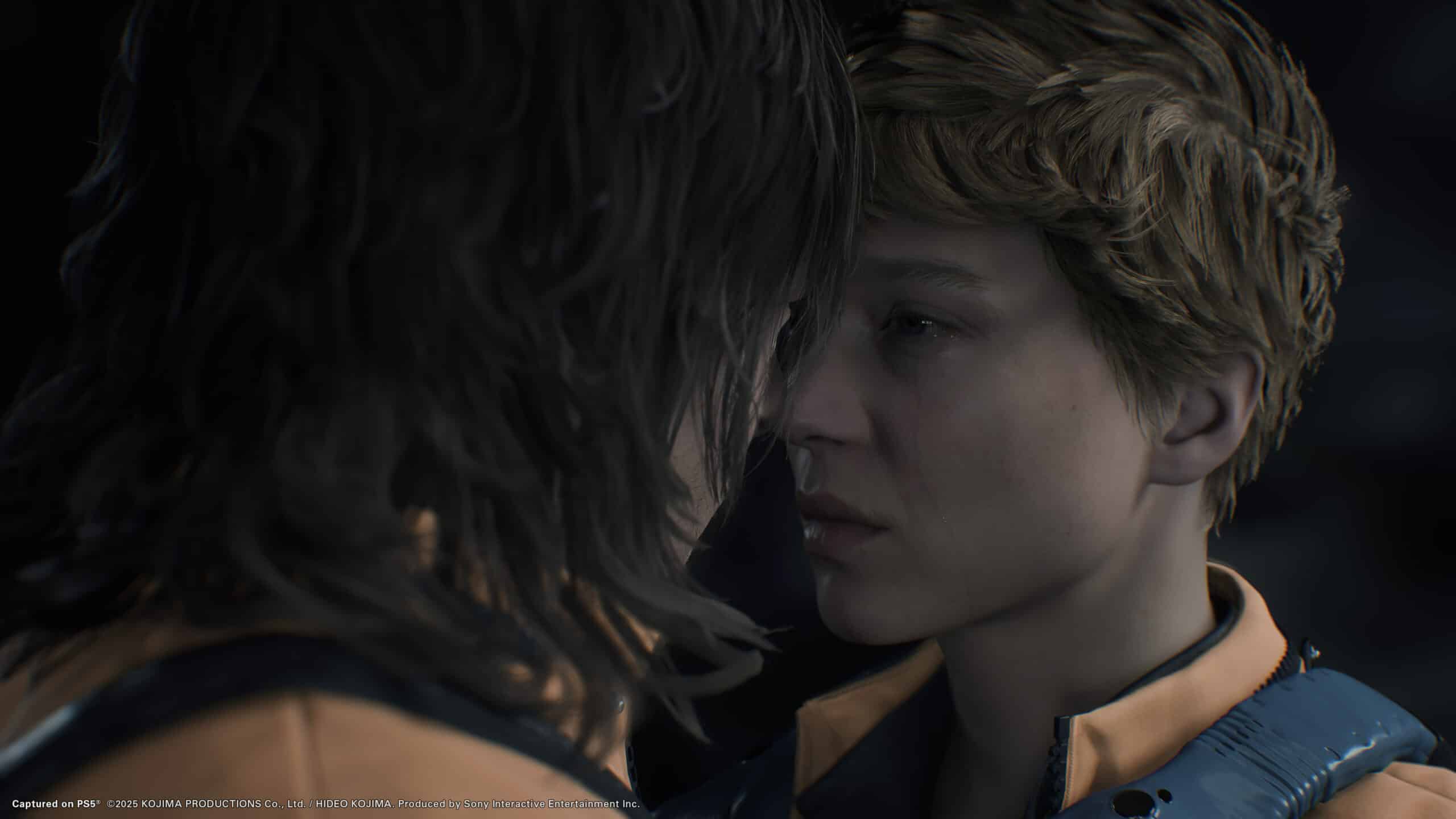 Two people intimately close, facing each other, wearing jackets with orange accents reminiscent of Death Stranding 2's style. The scene is dramatic and emotional.
