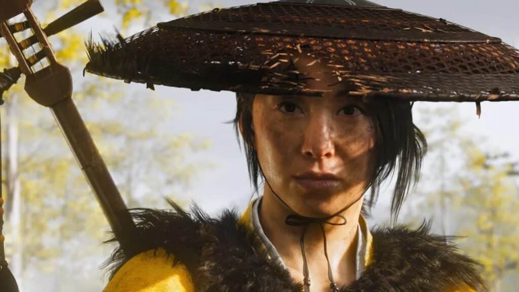 A person in a straw hat and fur-trimmed clothing stares intensely, holding a sword on their back, evoking the mysterious aura found in Ghost of Yōtei new details.