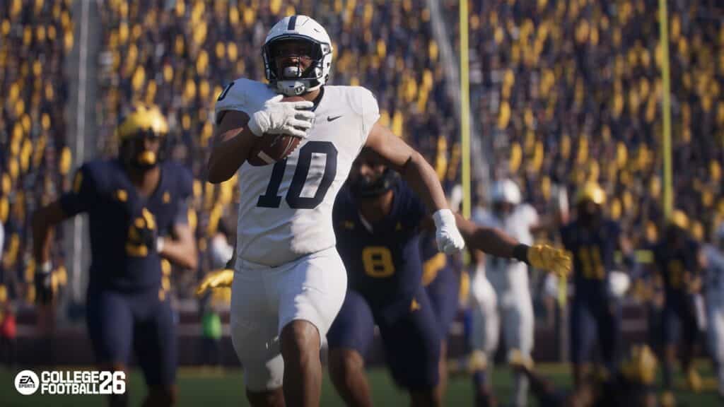 A football player in white runs with the ball as defenders in blue chase him, echoing the intensity seen in the College Football 26 trailer, amidst a roaring, crowded stadium.
