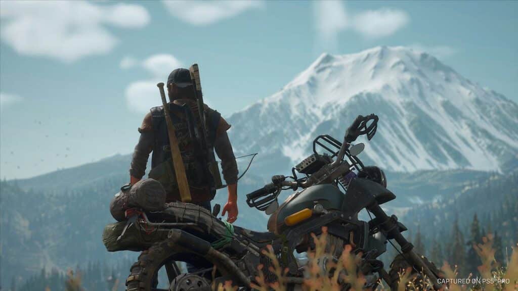 A person with a crossbow stands by a motorcycle, gazing at a snow-capped mountain in the distance—a scene reminiscent of Days Gone Remastered.