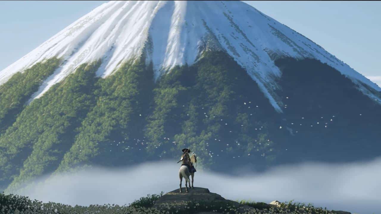 A person on horseback stands on a hill, gazing at the snow-capped Ghost of Yotei mountain rising majestically in the distance.