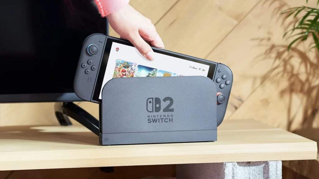 A person placing a Nintendo Switch into its dock on a wooden table beside a TV, perhaps curious about how the upcoming Nintendo Switch 2 specs will compare.