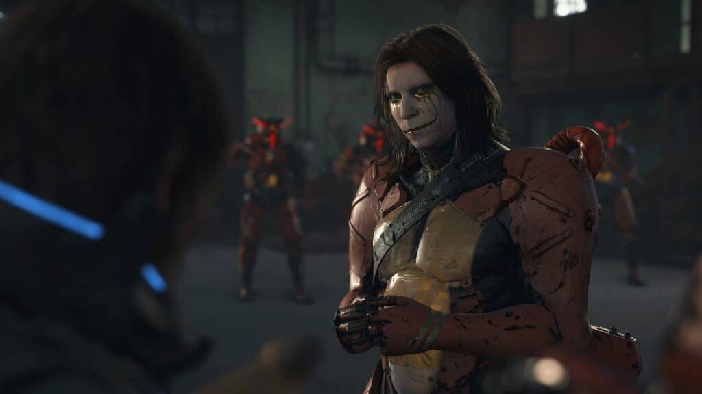 An armored figure with long hair and face paint from Death Stranding 2: On The Beach stands in focus; red-armored figures are blurred in the background.