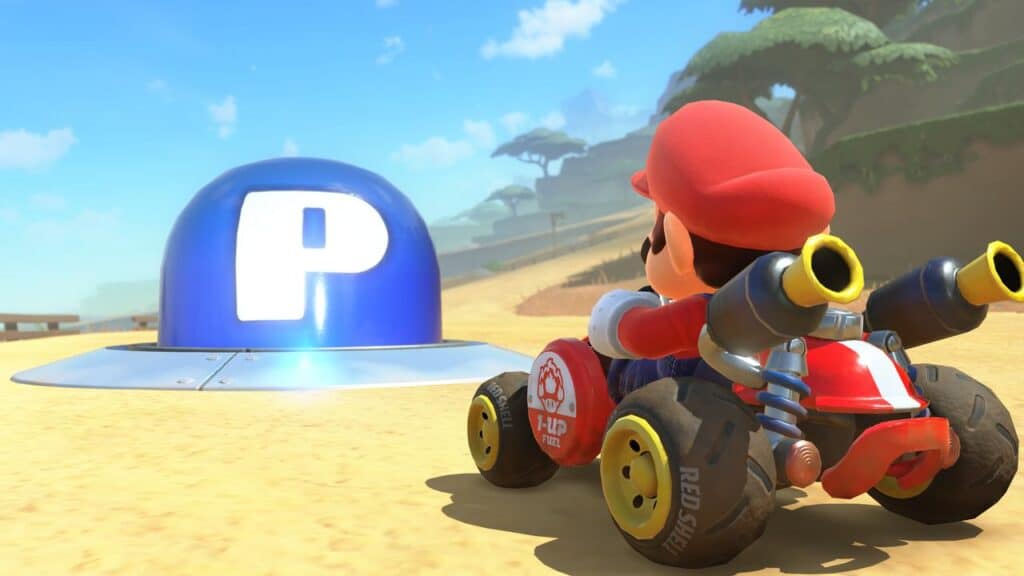 Mario in a go-kart speeds along a sandy track in Mario Kart World, approaching a large blue "P" button in this exciting video game scene.