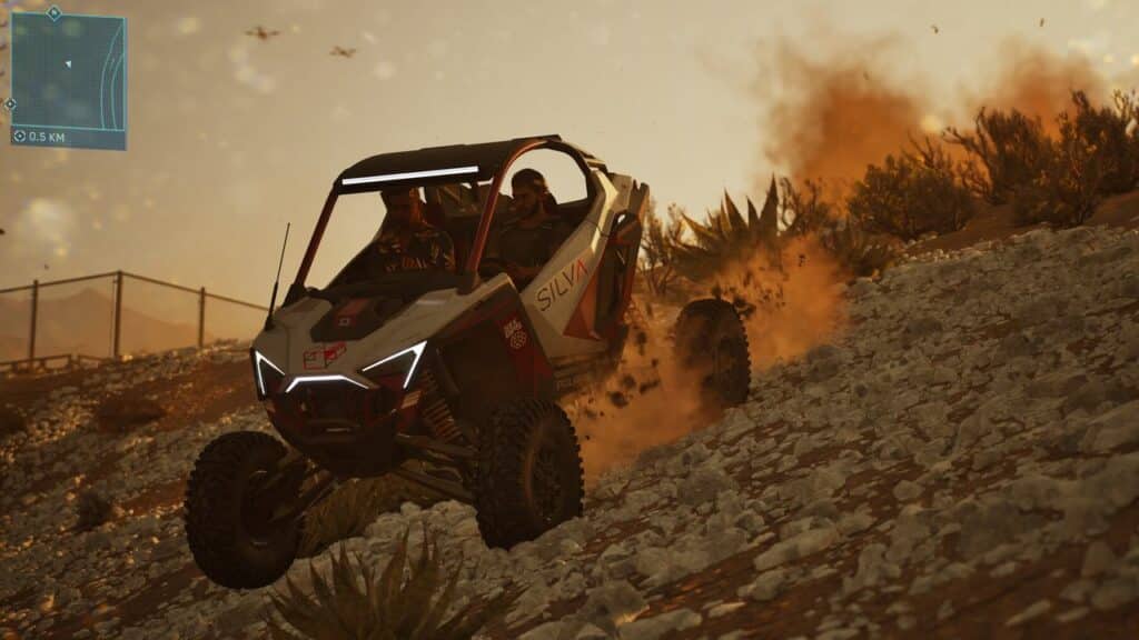 A Mindseye off-road buggy speeds down a rocky hill, kicking up dust at sunset with two people inside.