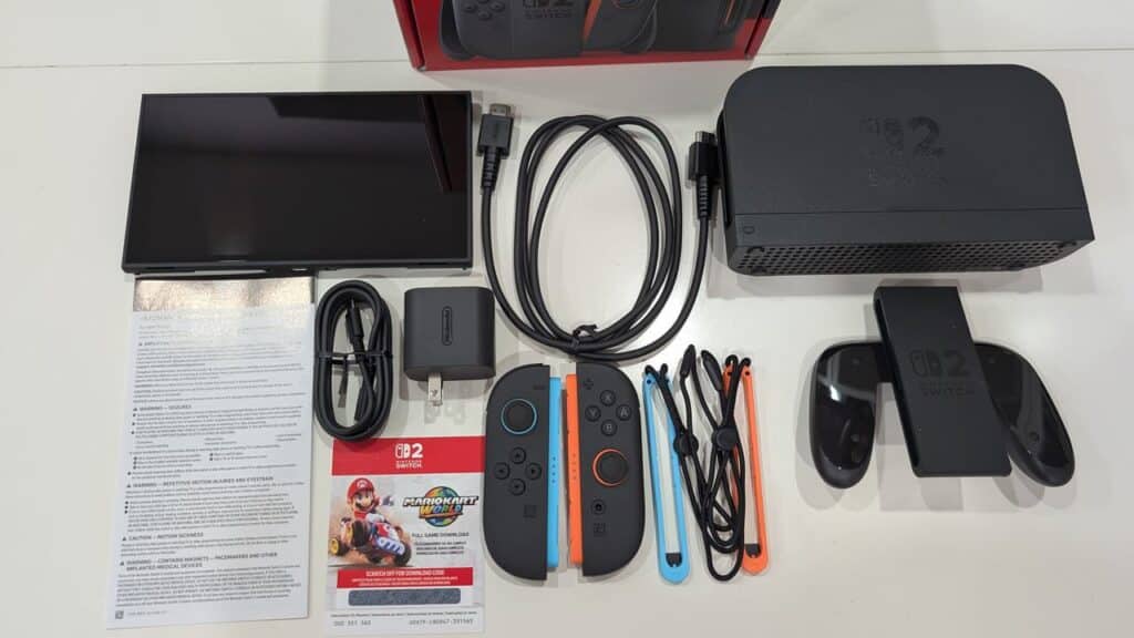 Nintendo Switch 2 console with dock, Joy-Cons, cables, grip, user manual, and Mario Kart 8 Deluxe game code—compatible with Nintendo Switch 2 for an enhanced gaming experience.