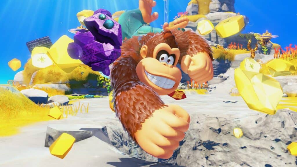 Donkey Kong punches forward in Donkey Kong Bananza, surrounded by yellow gems and bright, colorful scenery.