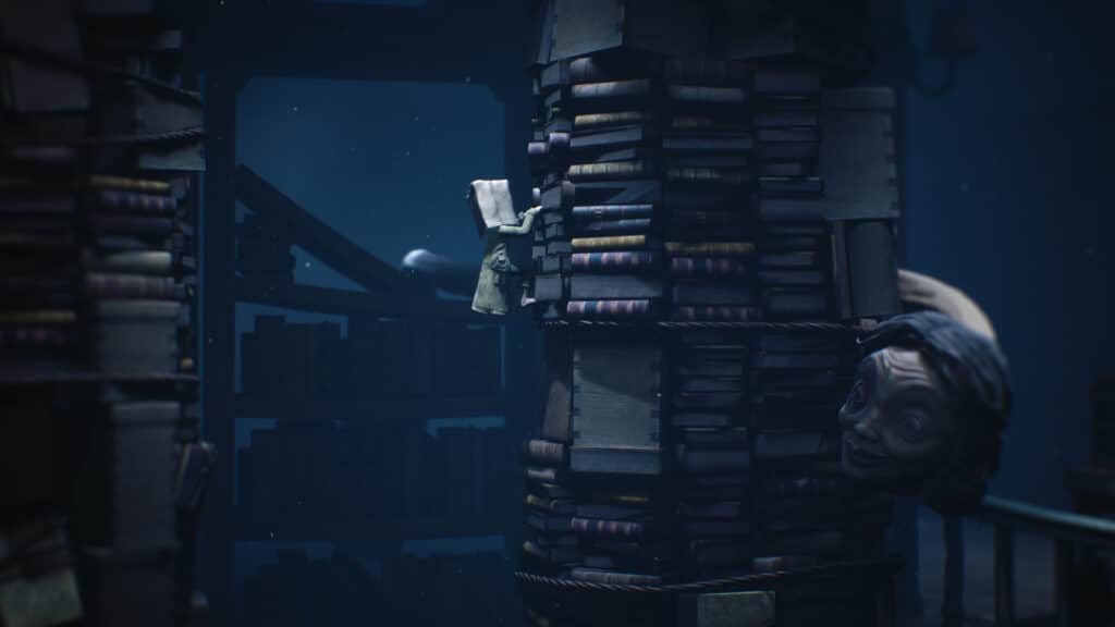 A small figure climbs a tower of books as a large, creepy head peers out from behind the stack in a dark room, evoking the eerie atmosphere of Little Nightmares II.