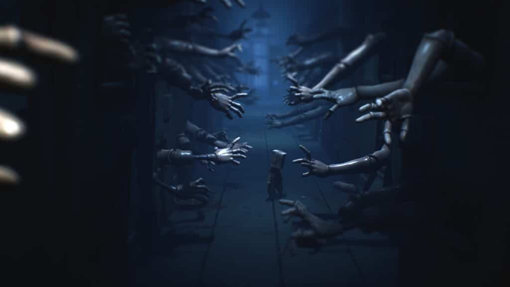 A small figure walks down a dark hallway in the haunting world of Little Nightmares II as hands reach out from the walls toward them.