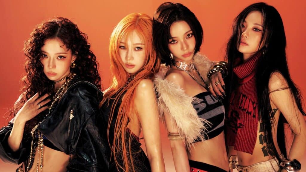 Four women from æspa pose confidently in edgy, stylish outfits against an orange background.