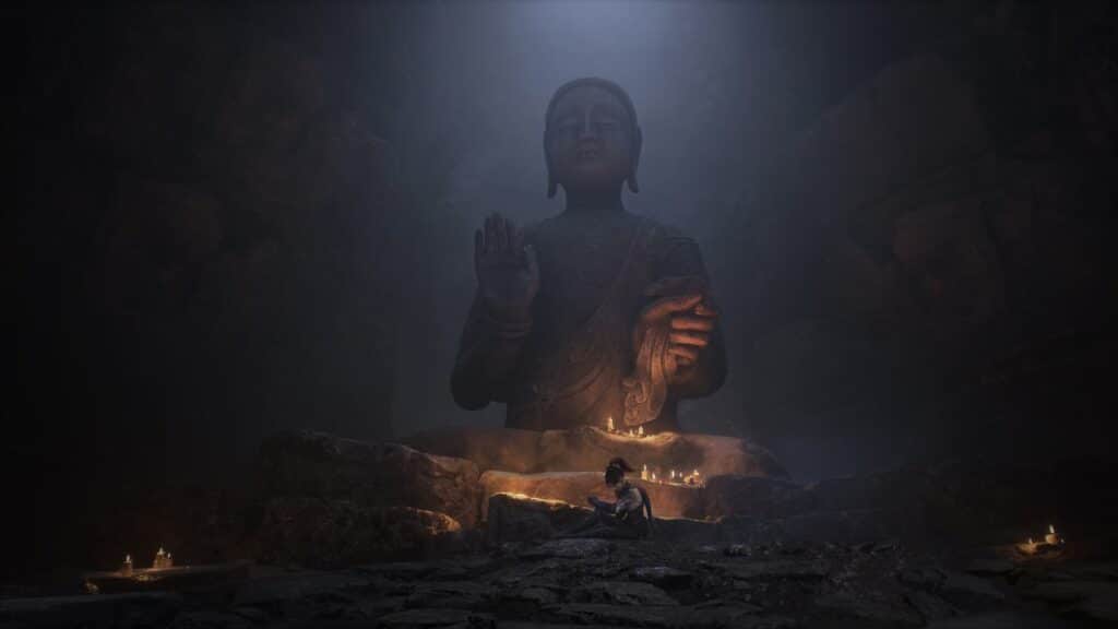 A person sits near candles in front of a large Buddha statue in a dimly lit, misty cave, evoking the mysterious world of WUCHANG Fallen Feathers.
