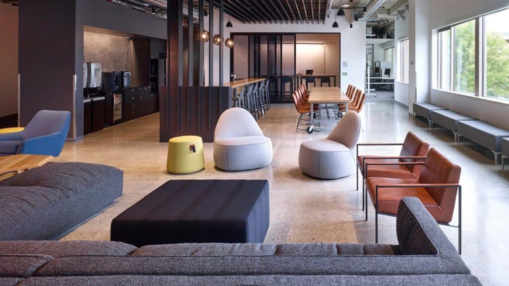 Modern open office lounge with various seating, large windows, and a long communal table in the background—a dynamic space reflecting adaptability amidst recent Xbox layoffs.