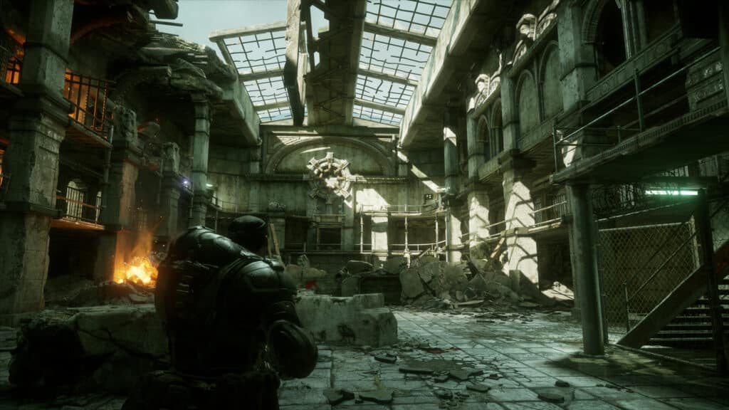 A soldier in armor stands in a ruined, sunlit building with debris and broken walls, evoking the intense atmosphere of Gears of War Reloaded.