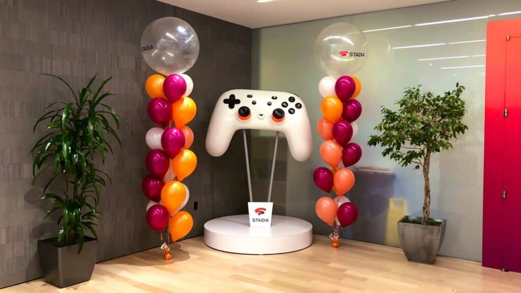 Colorful balloons and a large Stadia controller are displayed in an office with potted plants, once overseen by a former Google Stadia Community Manager.