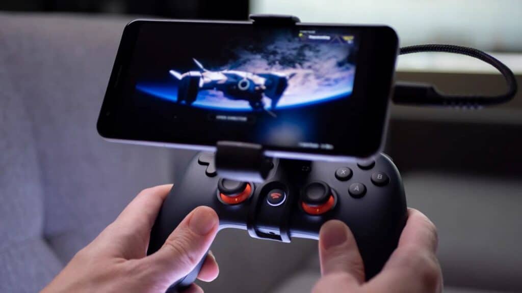 Hands holding a game controller with a smartphone showing a space game attached on top—a setup that would impress any former Google Stadia Community Manager.