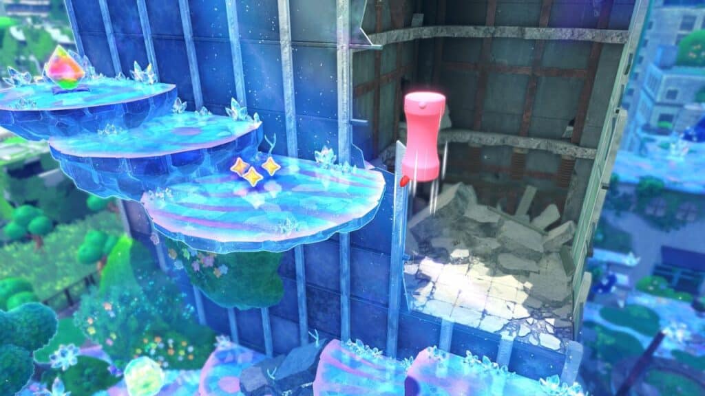 Kirby floats by an icy ledge on a tall, crumbling building in a colorful, overgrown city in Kirby and the Forgotten Land Nintendo Switch 2 Edition and Star-Crossed World.