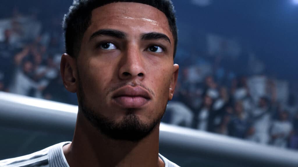 A close-up of a male soccer player with short hair and a trimmed beard, set against a blurred stadium crowd, captures the intensity of EA Sports FC 26.