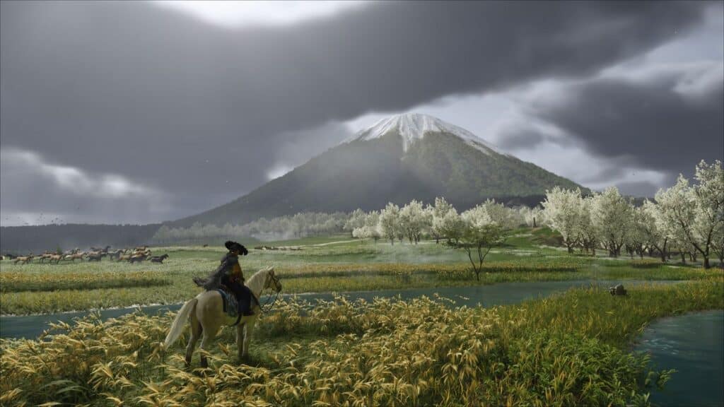 Atsu on horseback overlooks fields and trees with a mountain in the background, while the Ghost of Yotei lingers beneath a cloudy sky.
