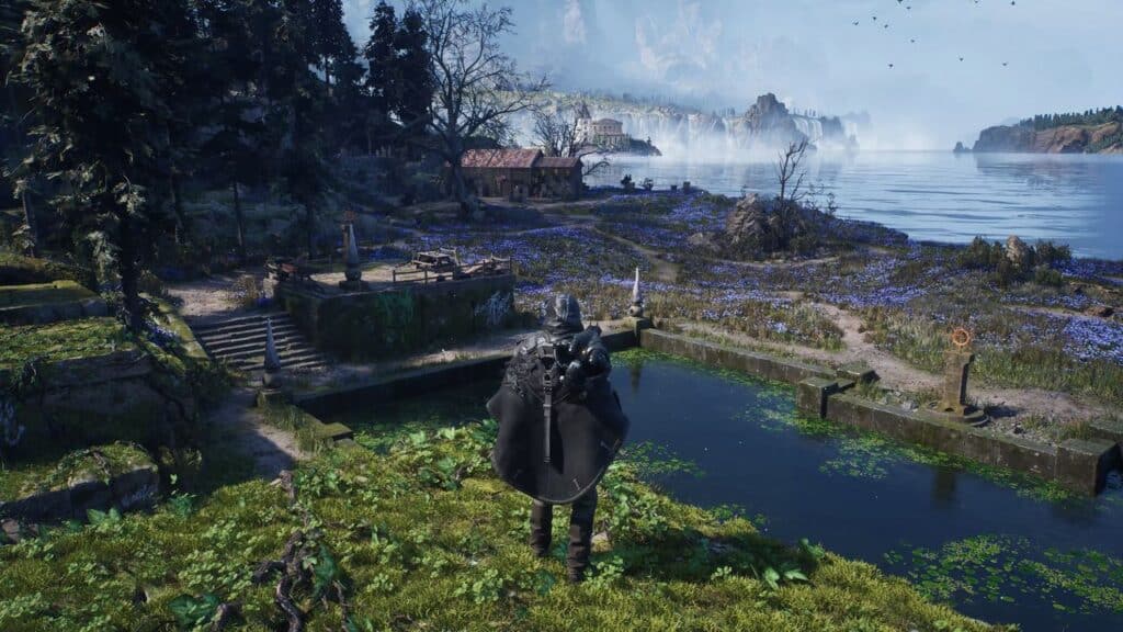 A cloaked figure stands near water, gazing at a scenic lakeside village with mountains in the distance, as if searching for answers in a world where Hell is Us.