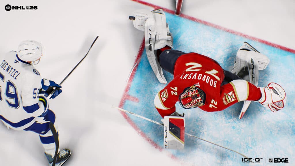 Hockey goalie in red blocks a shot as opposing player in white prepares to score in NHL 26 video game.