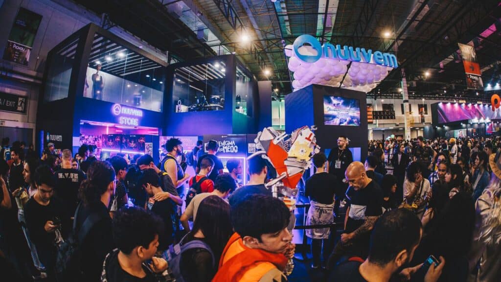 Crowd at a lively gaming convention with colorful booths, bright lights, and people in cosplay gathering for the Nuuvem spawnd interview.