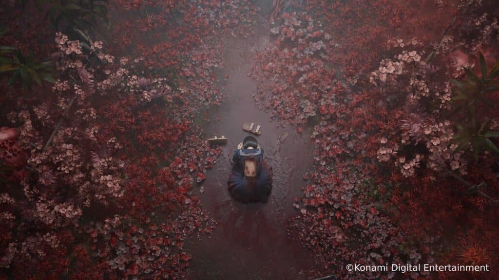 A person kneels on a path surrounded by red and pink flowers, viewed from above—a scene reminiscent of Silent Hill f’s hauntingly beautiful atmosphere.