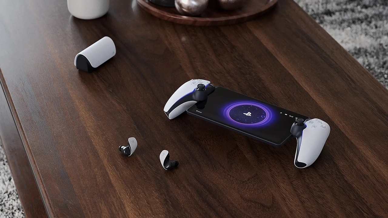 PlayStation Portal on a desk with wireless earbuds, and a charging case on a wooden table—showcasing some of the best PlayStation Portal accessories for your gaming setup.