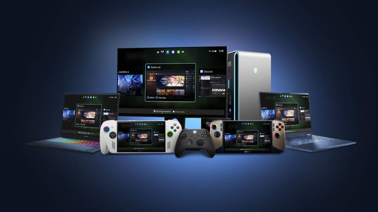 Various gaming devices, controllers, laptops, and a desktop arranged before a large monitor showcasing game screens for the full screen experience on Windows 11.