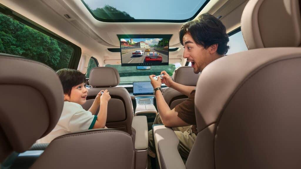 A man and child excitedly play a racing video game on a screen inside an XPENG car with a panoramic sunroof, powered by cloud gaming Xplay.