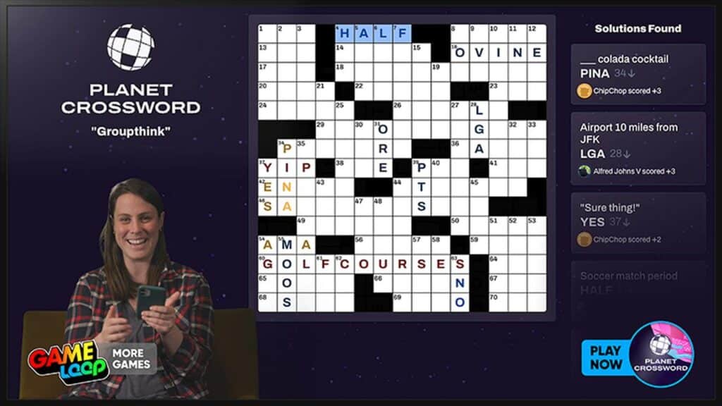 A woman plays a crossword puzzle game on her phone; the crossword is displayed on a large screen.