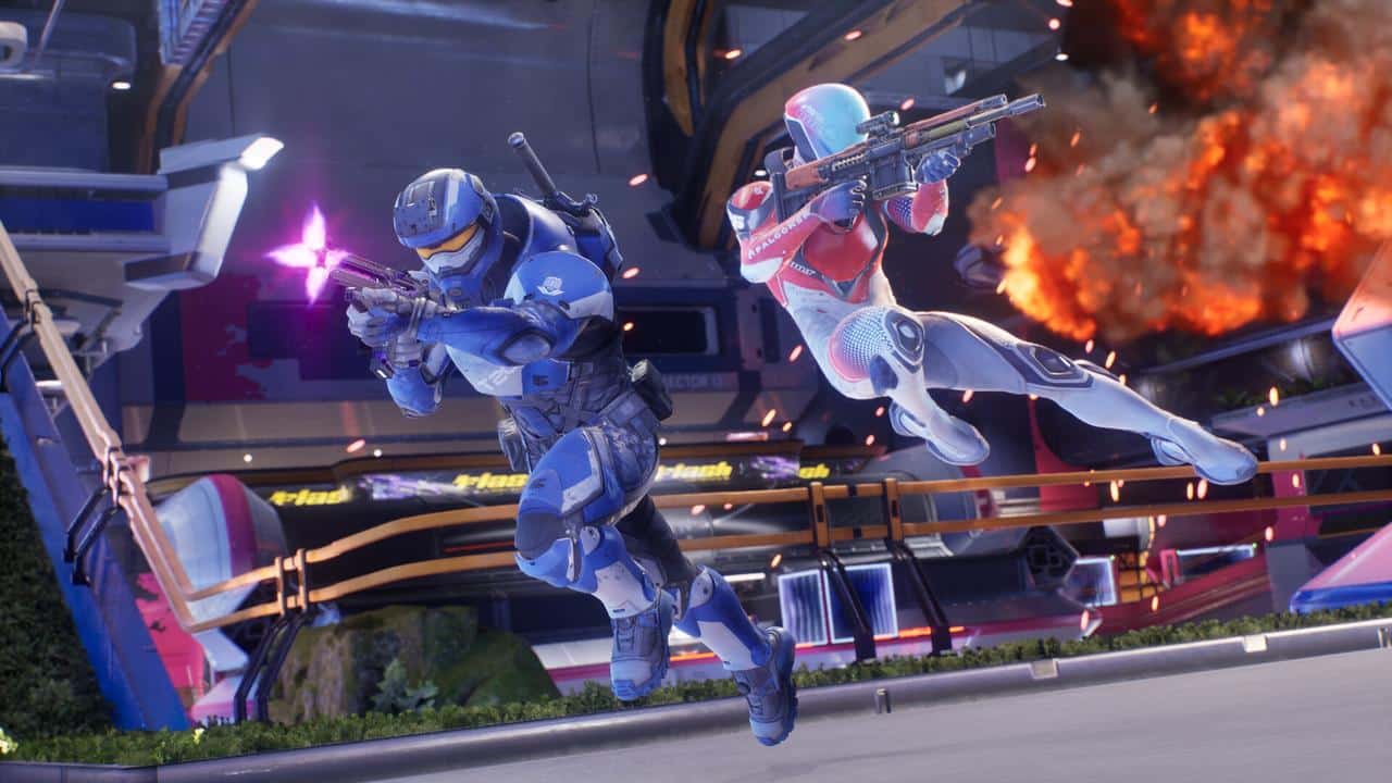 Two armored sci-fi soldiers leap and fire futuristic guns in a chaotic Splitgate: Arena Reloaded battle, as an explosion blazes behind them.