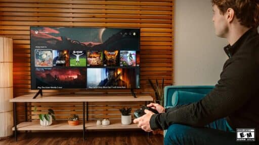 A person holding a game controller while browsing games on a large TV in a modern living room.
