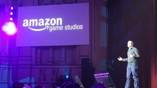 A person presents on stage next to a large screen displaying the Amazon Game Studios logo.