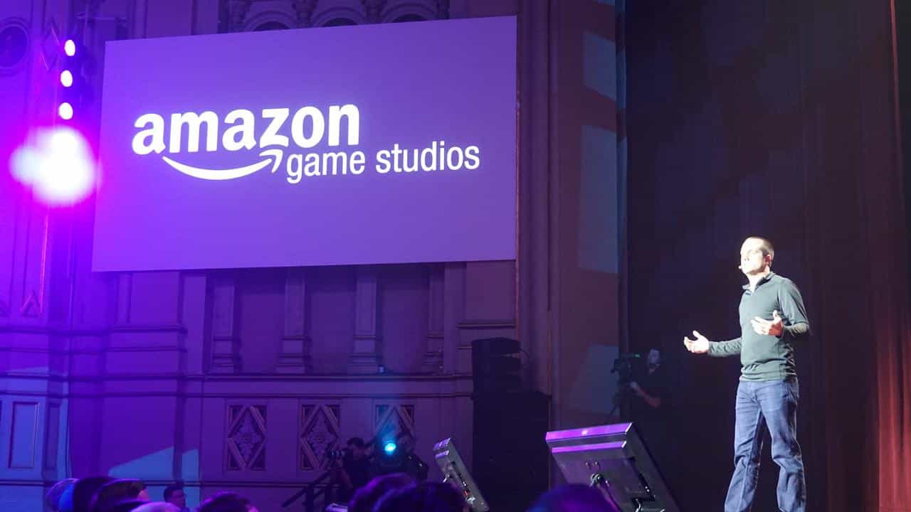A person presents on stage next to a large screen displaying the Amazon Game Studios logo.