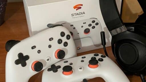 Two white Stadia controllers and a black gaming headset are placed in front of a Stadia Premier Edition box.