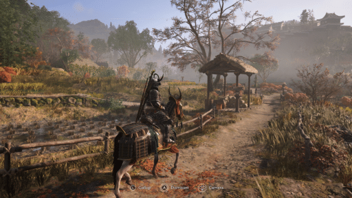 A samurai on horseback rides along a dirt path in a scenic, autumn countryside with mountains in the distance.