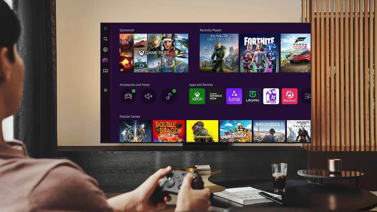 Person holding a game controller facing a TV screen displaying a gaming dashboard, showcasing various game icons—a modern look at cloud gaming distribution strategy in action.