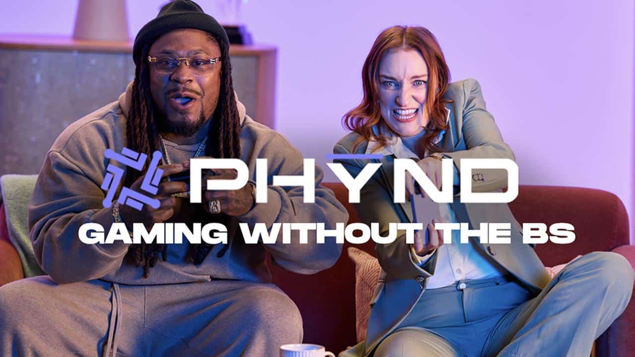 Two people excitedly play video games on a couch with the text "PHYND Gaming Without The BS" overlaid.