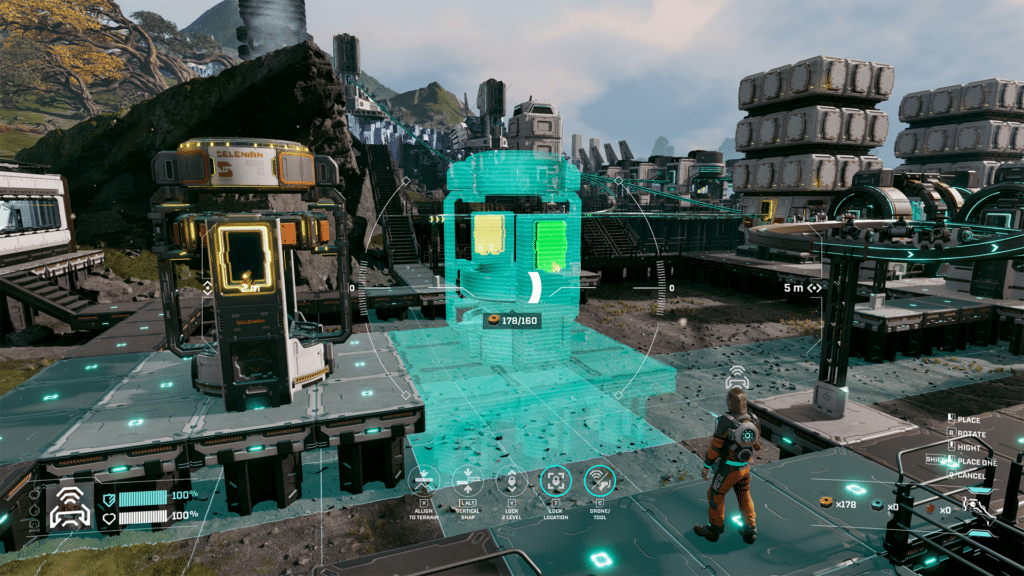 A player in a futuristic game environment is constructing a building with a holographic blueprint interface on a grid-like platform, surrounded by industrial structures and rocky terrain.