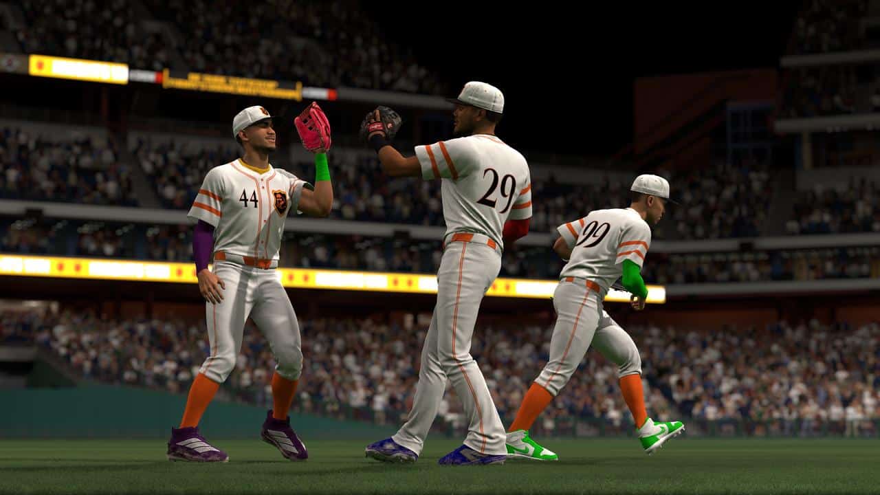 Three baseball players in white uniforms high-five each other on a field during a night game, capturing the excitement found in MLB The Show 26.